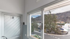 A room with a large window, a door with a handle, and a view of a street and buildings outside. - Vacation Studio 'Vv Faro' with Mountain View, Wi-Fi and Air Conditioning (Puerto de Mogán)