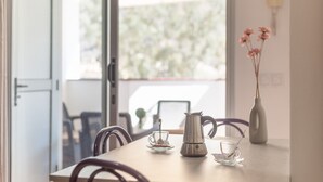 A dining table with a coffee pot, two cups, and a vase with flowers. - Vacation Studio 'Vv Faro' with Mountain View, Wi-Fi and Air Conditioning (Puerto de Mogán)
