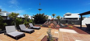 Eine Dachterrasse mit Liegestühlen, einem kleinen Pool und einem Steingarten.