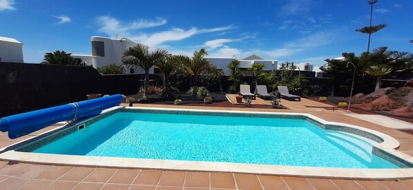 A swimming pool with lounge chairs, palm trees, and modern architecture in the background. - Vacation Villa 'Adais' with Private Pool, Wi-Fi and Air Conditioning (Playa Blanca)