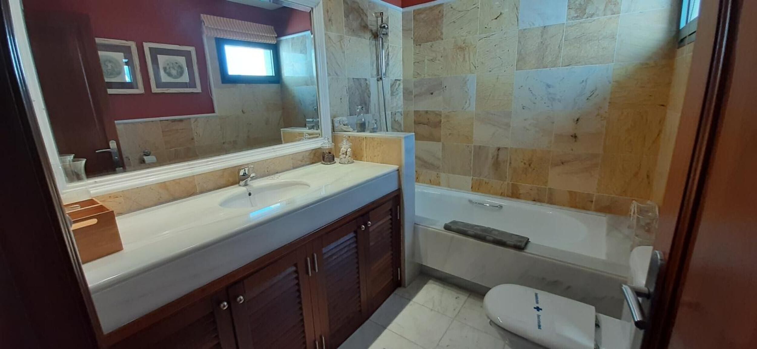 Een badkamer met een wastafel, een grote spiegel, een douche en een toilet.