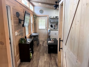 A wooden interior with a dining area, kitchen, and a door leading to another room. - Off-Grid, Lakeside Tiny Home in Punta Gorda, Florida, Perfect for a Weekend Getaway (Punta Gorda)