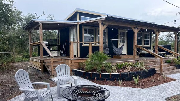 A wooden deck with Adirondack chairs and a fire pit. - Off-Grid, Lakeside Tiny Home in Punta Gorda, Florida, Perfect for a Weekend Getaway (Punta Gorda)