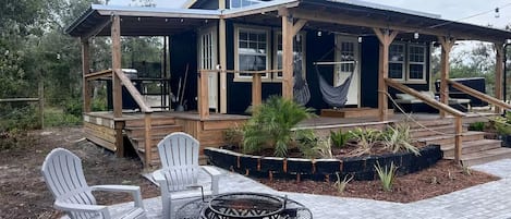 A wooden deck with Adirondack chairs and a fire pit.