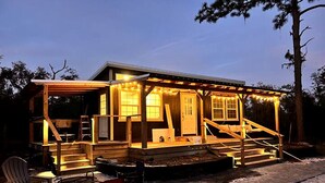 A wooden cabin with a porch, a fire pit, and a chair. - Off-Grid, Lakeside Tiny Home in Punta Gorda, Florida, Perfect for a Weekend Getaway (Punta Gorda)