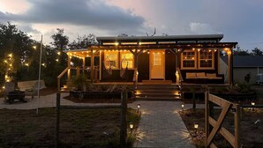 A house with a porch, outdoor seating, and string lights. - Off-Grid, Lakeside Tiny Home in Punta Gorda, Florida, Perfect for a Weekend Getaway (Punta Gorda)