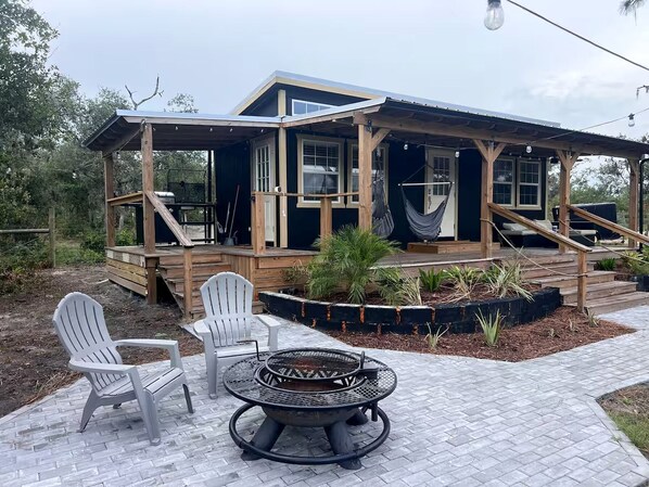 A wooden deck with Adirondack chairs and a fire pit.