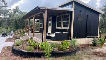 Een houten vakantiehuis met een veranda, een klein terras en een tuin vol planten.