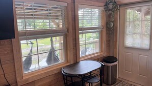 A room with wooden walls, a table with two chairs, a trash can, and a door with a window. - Off-Grid, Lakeside Tiny Home in Punta Gorda, Florida, Perfect for a Weekend Getaway (Punta Gorda)