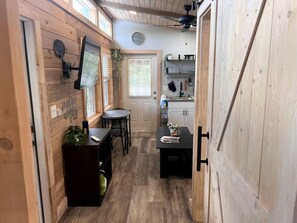 Un intérieur en bois comprenant un coin repas, une cuisine et une porte donnant sur une autre pièce.
