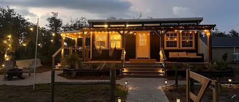Una casa amb un porxo, seients a l'exterior i llums penjades.