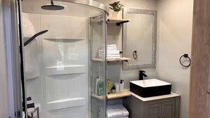 A bathroom with a glass shower enclosure, a sink, and a mirror. - Off-Grid, Lakeside Tiny Home in Punta Gorda, Florida, Perfect for a Weekend Getaway (Punta Gorda)