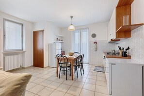 Una cocina compacta con una mesa, sillas, un refrigerador y una lámpara colgante.