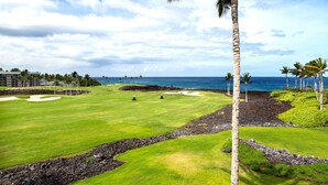 Un campo de golf con vistas al océano, palmeras y cielo despejado.