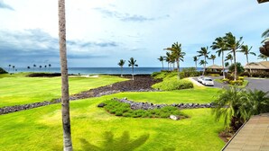 Campo de golf con vista al océano, palmeras y un edificio con techo.