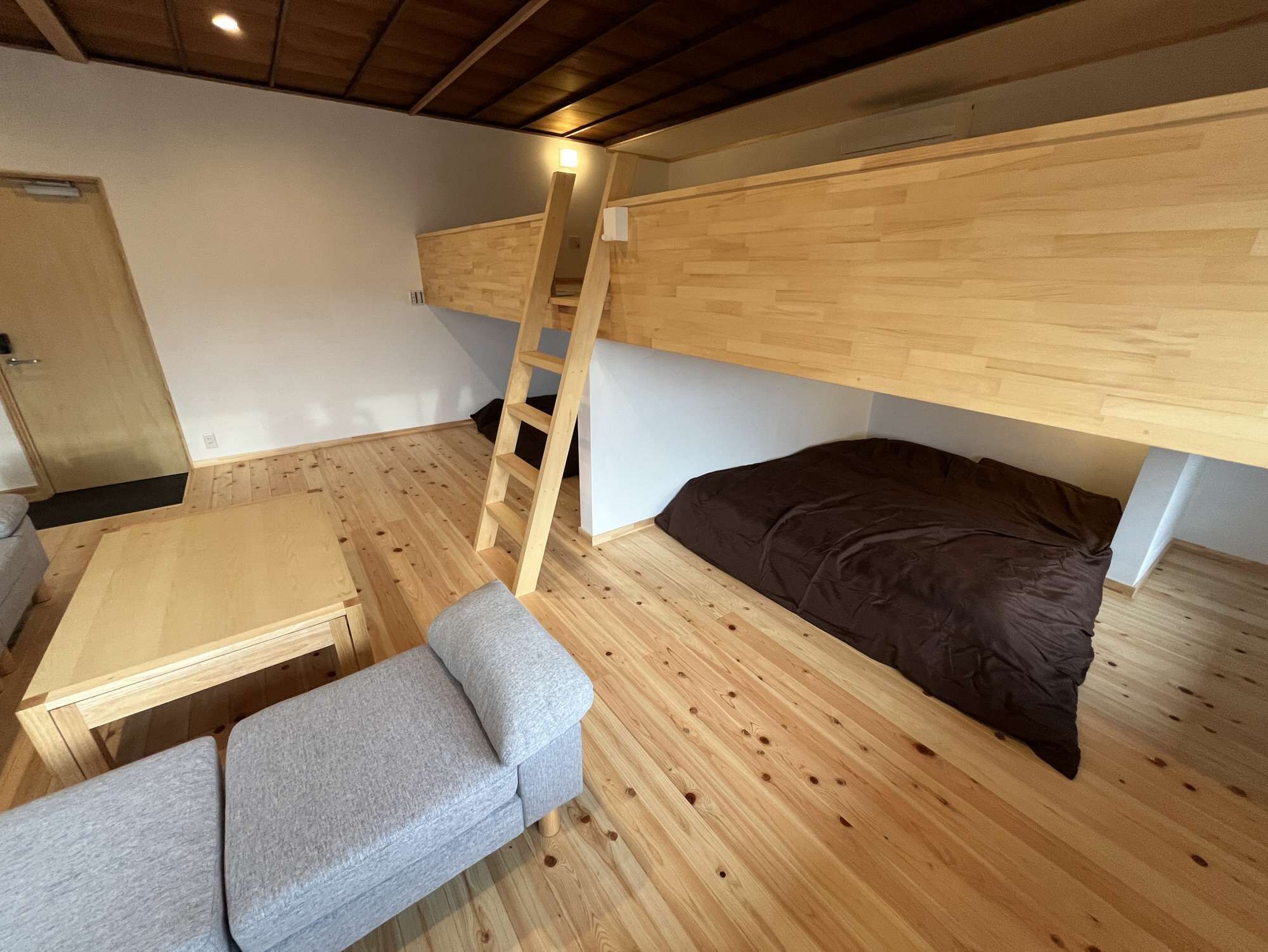 A compact room with a bunk bed, a small desk, and a bench.