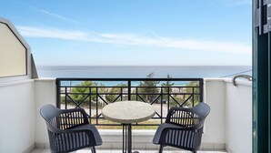 Un balcón con mesa y dos sillas, con vista al mar.