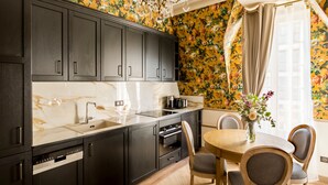 A modern kitchen with dark cabinets, a marble countertop, and a floral wallpaper design. - Merveil Signature Suite - Alfred (Paris)