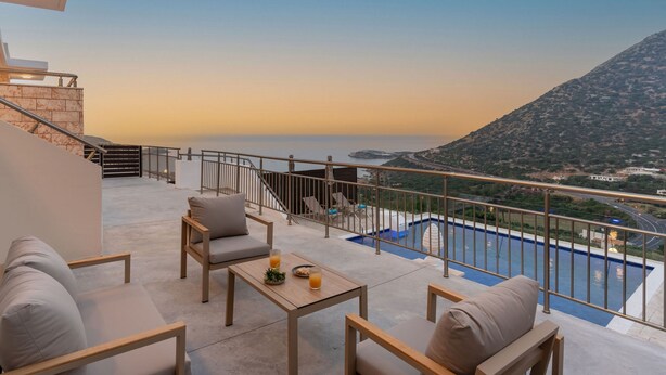 Ein Balkon mit Sitzgelegenheit und Blick auf Berg und Meer.
