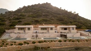 Eine moderne Villa mit Pool, zwei Schlafzimmern und Blick auf eine hügelige Landschaft.