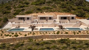 Eine moderne Villa mit Poolbereich, mehreren Sitzgelegenheiten im Freien und Blick auf eine hügelige Landschaft.
