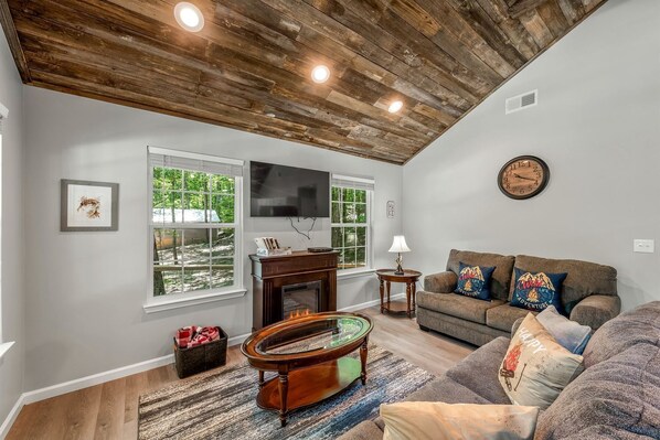 A living room with a fireplace, a sofa, a coffee table, and a television.