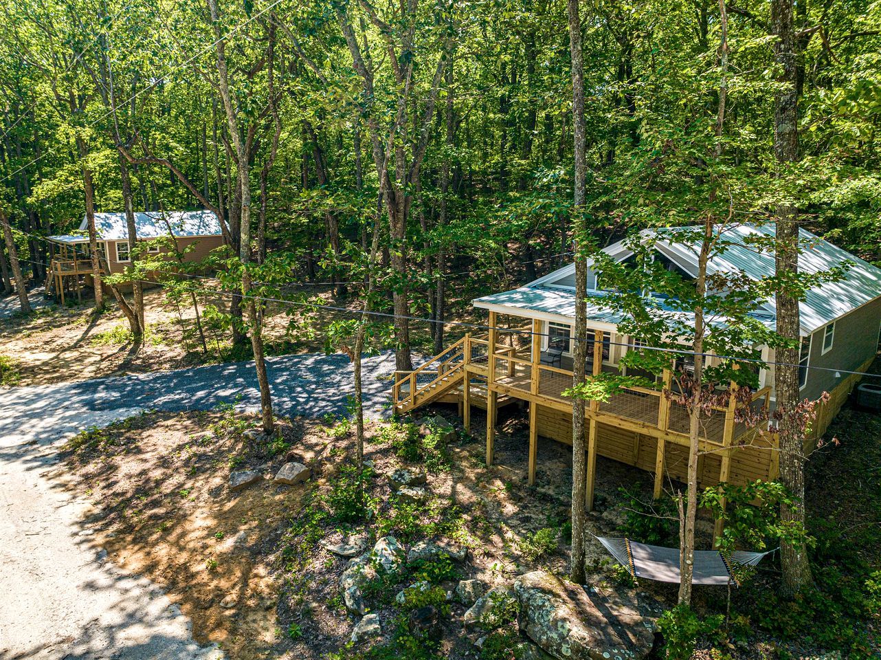 A cabin with a deck and a covered porch, surrounded by trees.