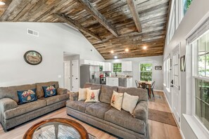 A spacious living area with a high ceiling, a kitchen, and a dining area.