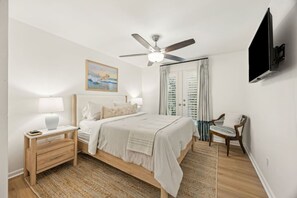 A bedroom with a bed, bedside tables, a chair, a ceiling fan, a TV, and a painting on the wall. - New Listing: 2/2 Blocks from Beach, Near Mayo (Sawgrass)