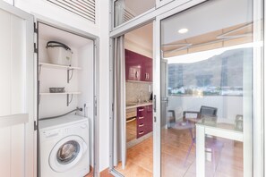 Een wasruimte met een wasmachine, een droogrek en een plank met een mand.
