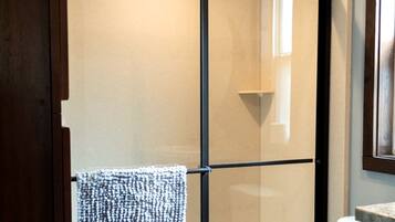 A bathroom with a glass shower enclosure, a towel hanging on a rack, and a marble countertop.