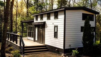 A modern, single-story cabin with a deck and a staircase leading to the entrance.