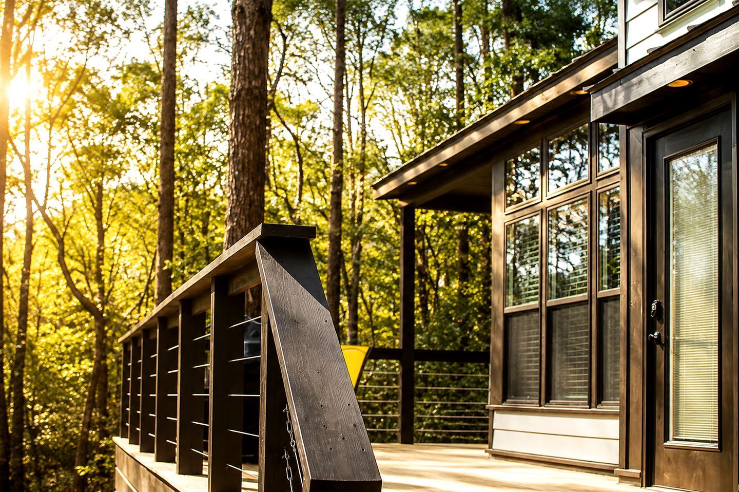 Ein modernes Gebäude mit großen Fenstern und einem Balkon mit Blick auf einen Wald.