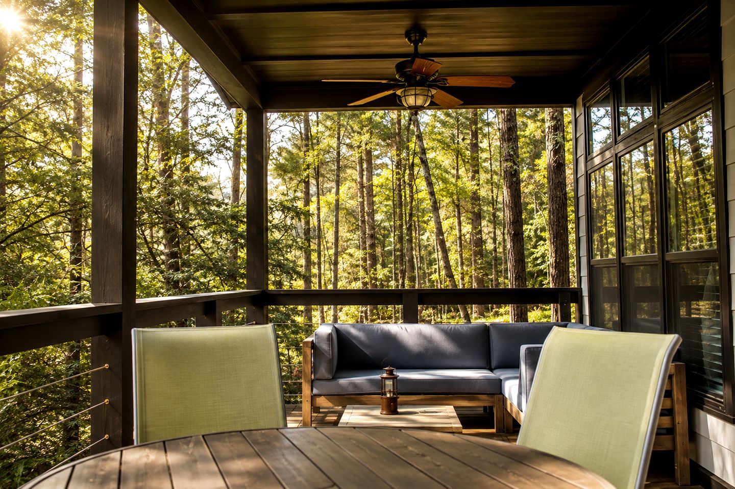Une terrasse en bois avec un canapé et des fauteuils, donnant sur une forêt.