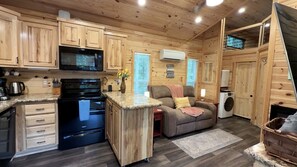 A compact kitchen with wooden cabinets, a microwave, stove, and a small island with a sink. - Peaceful Secluded Cabin with Hot Tub and Fantastic Views of the Surrounding Woods in Mentone, Alabama (Mentone)