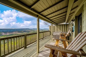 A covered outdoor deck with a hot tub, wooden chairs, and a view of the landscape. - Impressive Wooden Rustic Cabin with Fireplace in Mentone, Alabama (Mentone)
