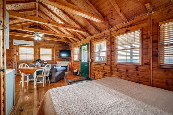 A log cabin interior with a bed, a dining area, a TV, and a fireplace. - Impressive Wooden Rustic Cabin with Fireplace in Mentone, Alabama (Mentone)