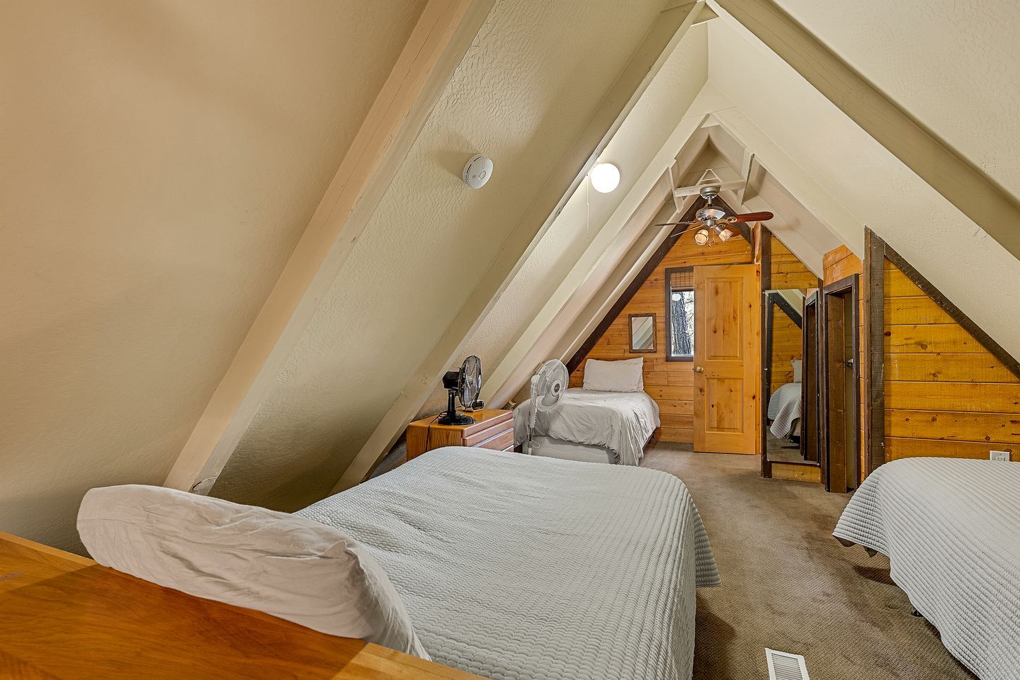 Ein Schlafzimmer mit zwei Betten, einer Holzbalkendecke und einem kleinen Fenster.