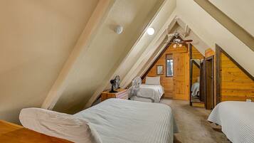 Ein Schlafzimmer mit zwei Betten, einer Holzbalkendecke und einem kleinen Fenster.