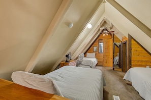 Ein Schlafzimmer mit zwei Betten, einer Holzbalkendecke und einem kleinen Fenster.