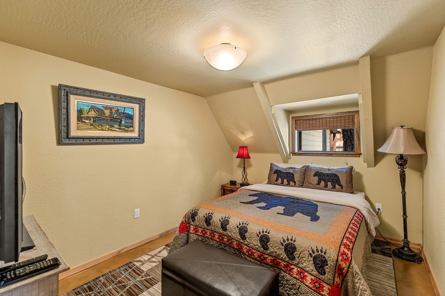 A bedroom with a bed, a painting, a window, a lamp, and a television.