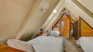 Un dormitorio con dos camas, techo de madera y una ventana pequeña.