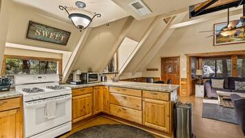 A kitchen with a stove, microwave, and wooden cabinets.