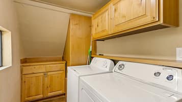 A laundry room with wooden cabinets and a front-loading washer and dryer.