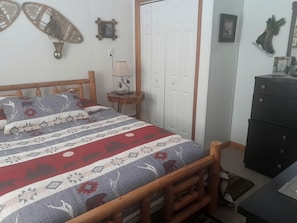 Een slaapkamer met een bed, een dressoir, een lamp en een deur.