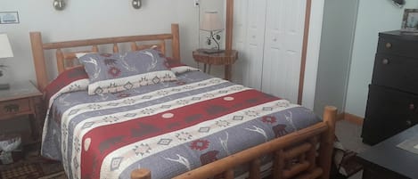 Un dormitorio con una cama de madera, una mesita de noche, una lámpara, un aparador y una puerta.