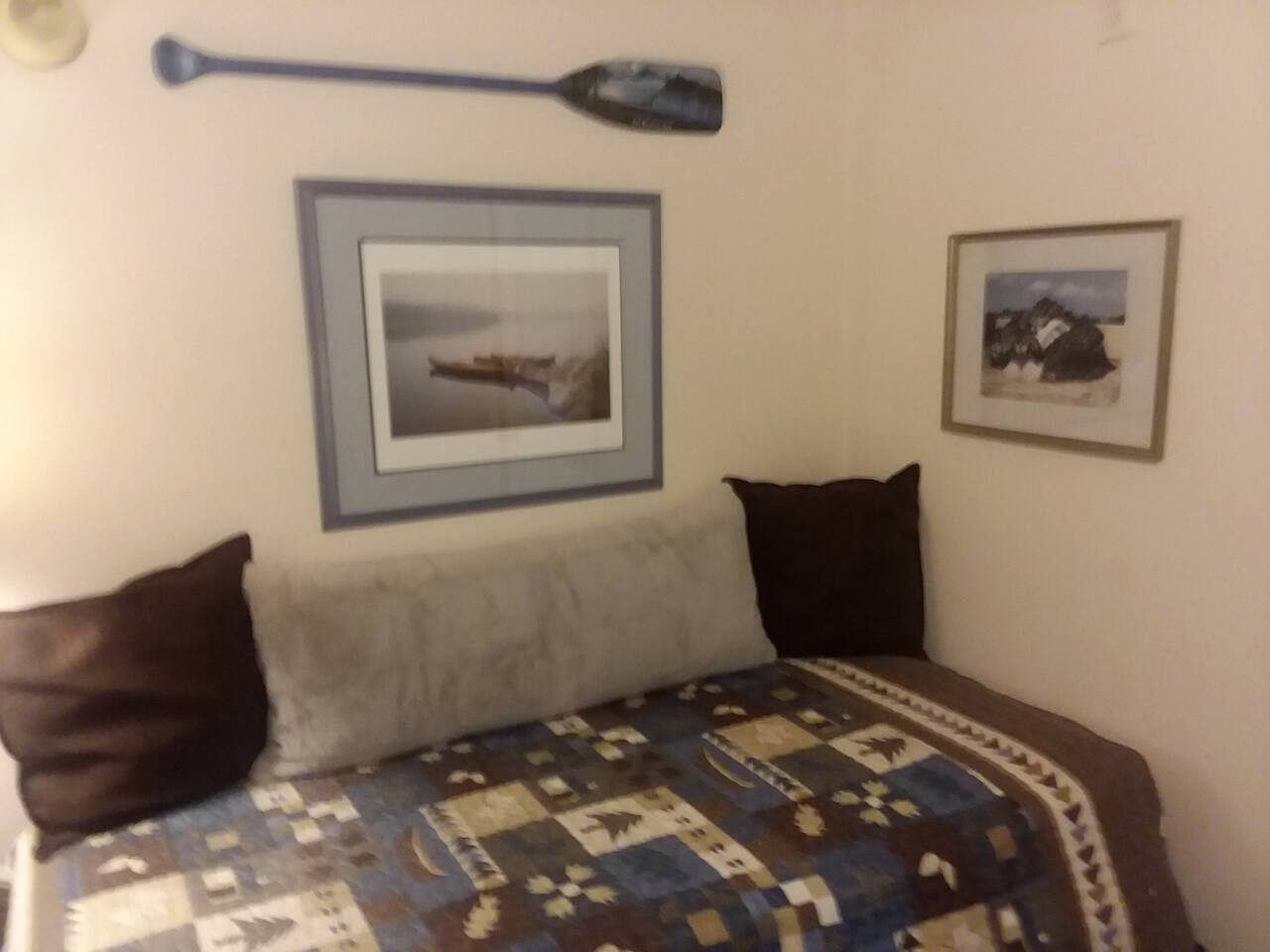 Une chambre à coucher avec un lit, des oreillers, une couette et deux tableaux encadrés accrochés au mur.