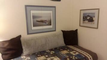 Une chambre à coucher avec un lit, des oreillers, une couette et deux tableaux encadrés accrochés au mur.