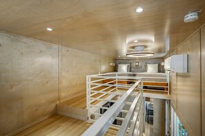 Un letto a castello con una scala, pareti in legno e un soffitto con faretti.