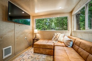 Una habitación acogedora con un amplio ventanal, un televisor de pantalla plana, un sofá y una lámpara.